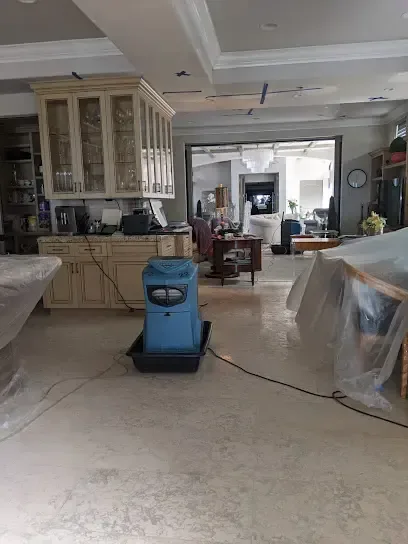 A dehumidifier and plastic containment in an open kitchen and family room during a dry-out