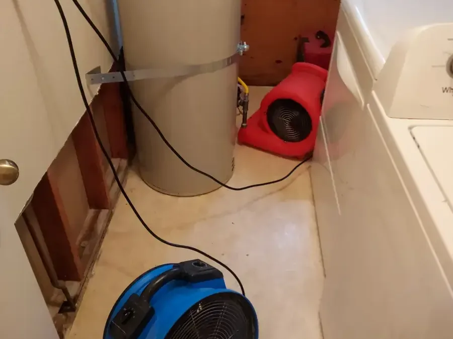 Air movers drying a laundry area with the wall opened behind the washer