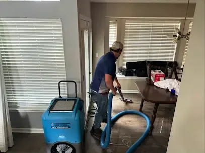 Technician running an extraction hose beside a dehumidifier in a living room