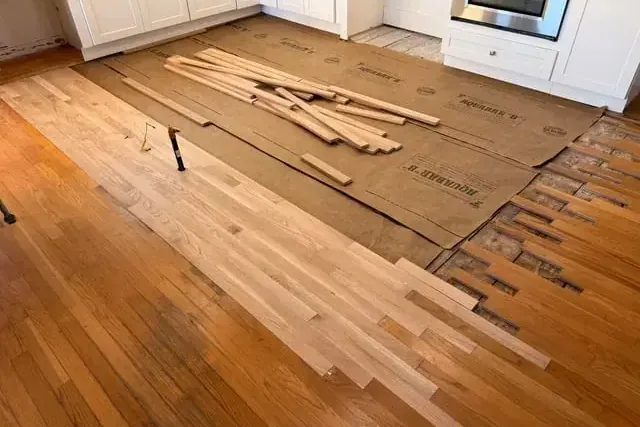 Kitchen hardwood flooring pulled up after a leak near the cabinets